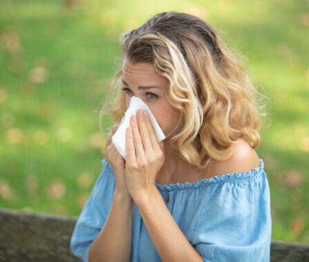Woman blowing nose outside