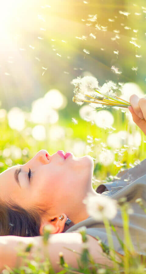 Woman lying in meadow blowing dandelions