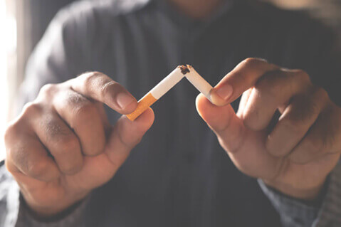 man breaking a cigarette in half
