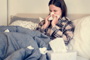 woman in bed blowing her nose
