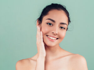 woman smiling and touching her face